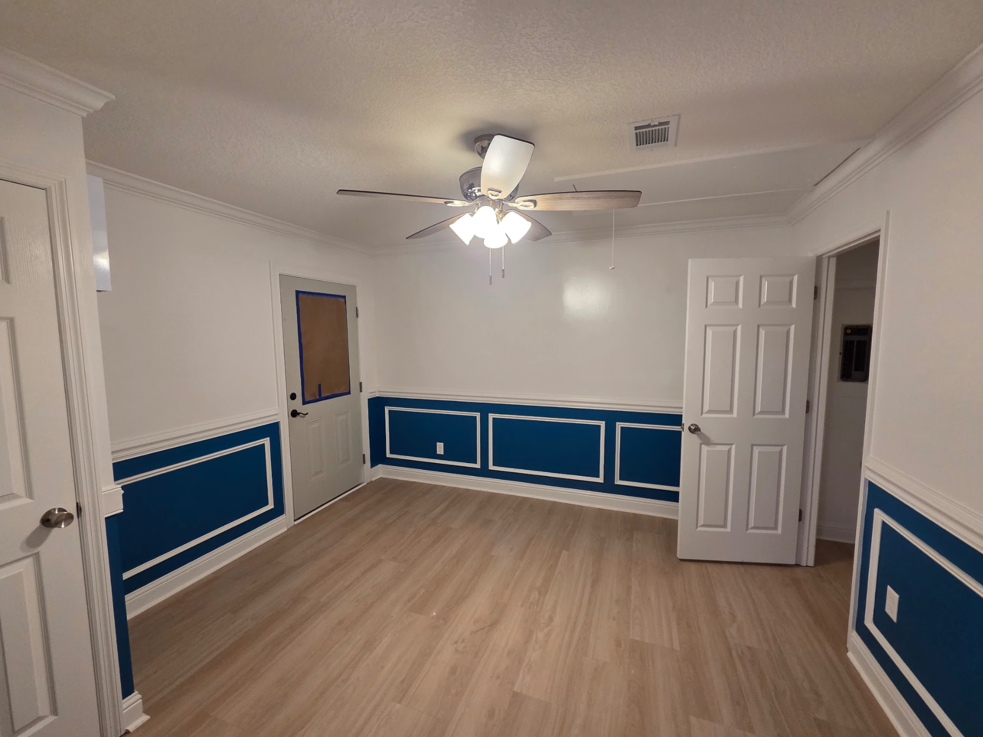 Installed flooring and white baseboards in a room with blue wall trim